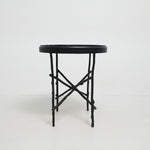 Eichholtz Tomasso Round Side Table with a black marble top and a black metal base resembling intertwined branches.